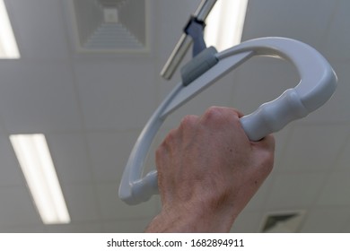 Patient Hand Holding Hospital Bed Trapeze In Intensive Care Unit ,  On Background Ceiling Lights 