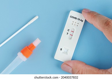 Patient hand showing positive test on Covid-19 nasal swab test kits or SARA-CoV-2 antigen rapid test on blue background.