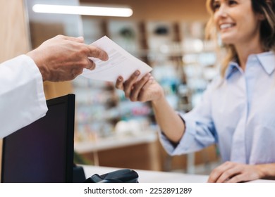 Patient handing a pharmacist a doctor's prescription in a chemist. Healthcare worker dispensing medication in a drug store. - Powered by Shutterstock