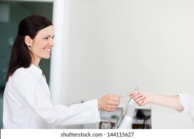 Patient Hands Insurance Card To Medical Assistant
