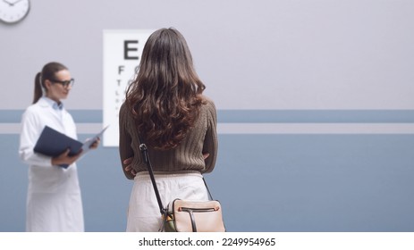 Patient having an eye exam and testing vision with a professional optometrist, she is reading the eye chart - Powered by Shutterstock