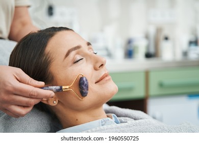 Patient Having Her Cheek Massaged With An Amethyst Roller