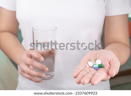 The patient is holding a glass of water and a large amount of medicine in his other hand. consuming a lot of pills concept. medicine in old man hand. The concept of medicine, health care, vitamins.