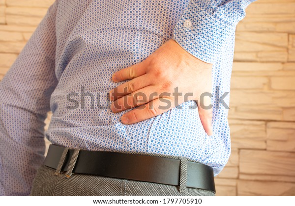 \
Patient holds right side with his hand in\
tilted position. Concept photo of pain in right side of abdomen due\
to diseases of kidneys, large intestine, pathology of nerve roots,\
radiculopathy\
shingles