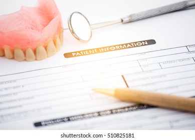 Patient Information Form And Dentures With Dental Glass With Pen On White Background