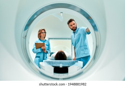 The Patient Lies On CT Or MRI, The Bed Is Moved Inside The Machine, Scanning Her Body And Brain Under The Supervision Of A Doctor And A Radiologist. In A Medical Laboratory With High-tech Equipment.