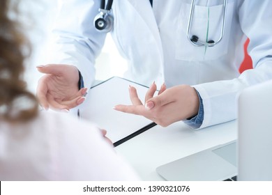 Patient hört einem weiblichen Arzt aufmerksam zu, der die Symptome des Patienten erklärt oder eine Frage stellt, während er gemeinsam in einer Konsultation diskutiert.