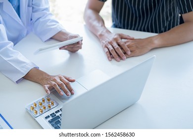 Patient Listening Intently To A Male Doctor Explaining Patient Symptoms Or Asking A Question As They Discuss Paperwork Together In A Consultation