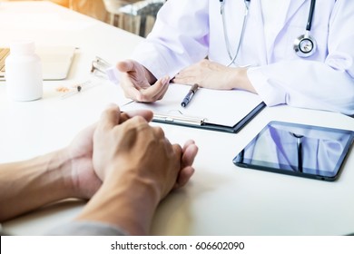 Patient Listening Intently To A Male Doctor Explaining Patient Symptoms Or Asking A Question As They Discuss Paperwork Together In A Consultation