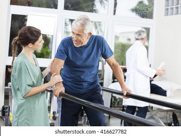 Patient Looking At Female Physiotherapist While Walking Between 