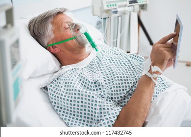 Patient Is Lying In Bed Reading Wearing An Oxygen Mask In Hospital Ward