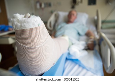 Patient Lying In Hospital Bed With Broken Leg Bone Wrapped In Ca