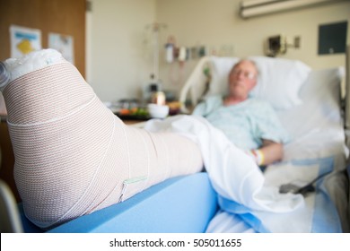 Patient Lying In Hospital Bed With Broken Leg Bone Wrapped In Ca