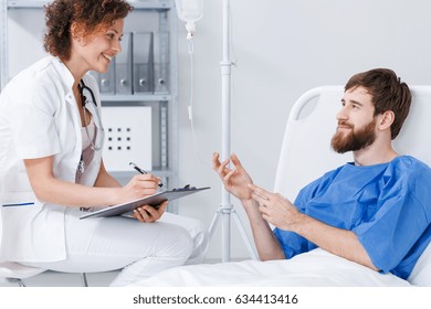 Patient Lying In Hospital Bed On Drip Talking With Friendly Nurse
