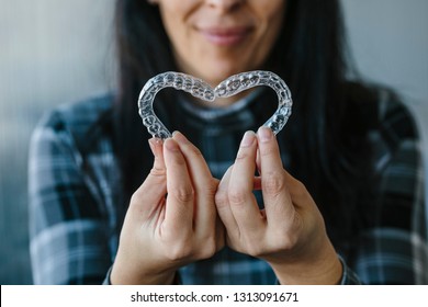 Patient making a heart shape with dental aligners