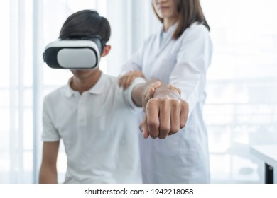 Patient Male Hand With VR Box, Female Doctor Doing Physical Therapy By Extending The Hand, The Concept Of Technology Helped The Feeling As If A Doctor Came To Treat At Home.