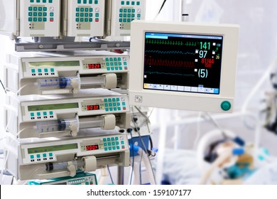 Patient With Monitor And Infusion Pumps In An Intensive Care Unit