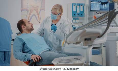 Patient with mouth open receiving examination from dentist at oral care clinic, using dental instruments. Orthodontist consulting man with toothache for dentistry diagnosis. Dentition work