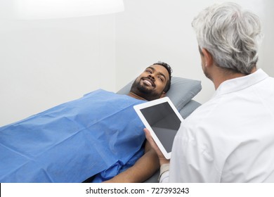 Patient On Bed Looking At Doctor Using Digital Tablet