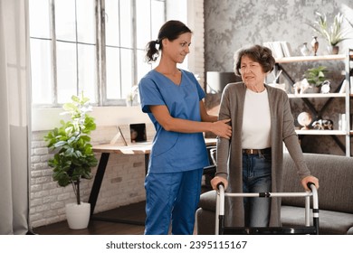 Patient in pain. Medical worker caretaker nurse supporting helping aiding senior woman grandmother with walking frame after injury trauma in hospice - Shutterstock ID 2395115167