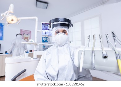 Patient Pov Of Dentist Explaining Teeth Treatment Dressed Up In Covid Protective Suit. Stomatolog Wearing Safety Gear Against Coronavirus During Heatlhcare Check Of Patient.