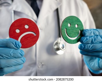 Patient Satisfaction Survey. Doctor Holds Joyful And Sad Emoticons.