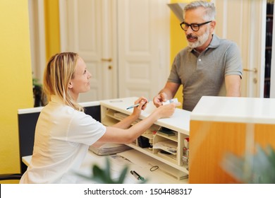 Patient settling up with a receptionist in a medical surgery after an examination by a doctor or dentist - Powered by Shutterstock