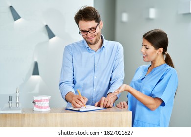 Patient signing documents in dental clinic - Powered by Shutterstock