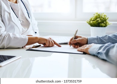 Patient signs a document with his doctor in medical office - Shutterstock ID 1373531759