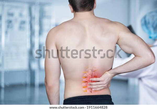 The patient stands and holds on to the spine\
on a blurred background.