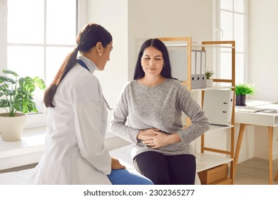 Patient suffering from stomach ache having consultation with female doctor in medical office. Young woman visiting gastroenterologist, gynecologist, therapist, GP in medical clinic - Shutterstock ID 2302365277