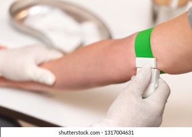 Patient with a tourniquet band on the arm, medical office or clinic, closeup