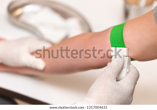 Patient with a tourniquet band on the arm,\
medical office or clinic,\
closeup