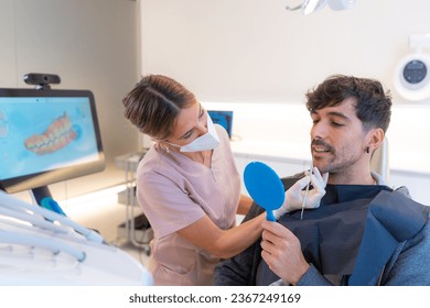 Patient using a mirror to look at the dental results in a dental clinic - Shutterstock ID 2367249169
