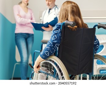 Patient in wheelchair at the hospital, a woman and the doctor are discussing in the background, back view