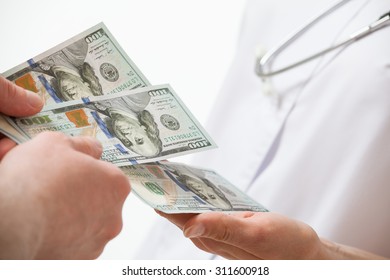 Patient's hand giving a money to doctor, white background