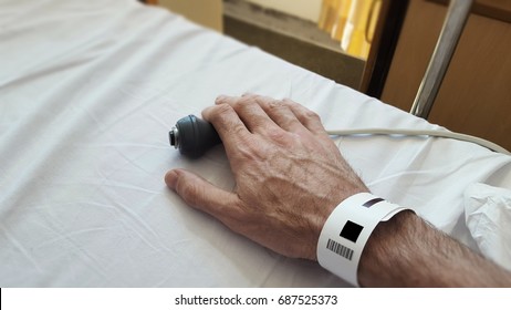 Patients hand on nurse call button in a hospital bed, Blurred foreground