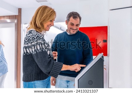 Patients smiling while scheduling appointments at the hospital using a modern machine in the hall
