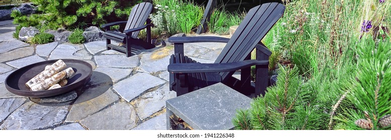Patio with Adirondack Chair And Fireplace Pit. Muskoka Chair On the Garden Tiled Patio Made From Stone Slabs. Fire Place Pit And Wooden Chairs in Backyard Garden.