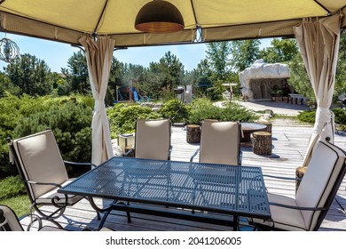 Patio With Dining Table In Garden Tent And BBQ Area In Backyard Of Country Mansion