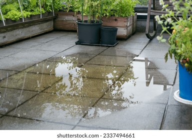 Patio drain clogged and flooded after heavy rain. Overflown drainage causing to pool large amount of water on tiles. Unclogg the drain from mud or dirt or plumber has to snake pipe. Selective focus. - Powered by Shutterstock