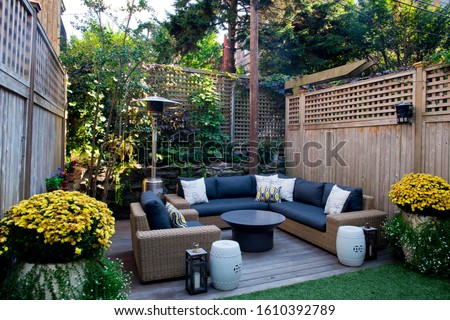 Patio. Garden. Urban, neutral, outdoor living space. Exterior photo. Outdoor living room with couch, comfy cushions, throw pillows, love seat, chairs and coffee table. Backyard with greenery, plants.