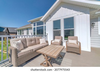 Patio Of A House On A Wooden Deck With Railings And Woven Furnitures