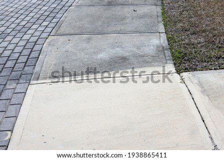 Patrially cleaned and partial irty cement sidewalk in front of a homeafter some of it has been pressure washed.