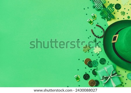 Patrick Day festive green background decorated with shamrocks, leprechaun hat, golden coins and gifts top view.