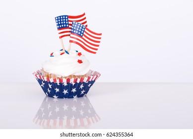 Patriotic 4th of July cupcake with decorative American flags against white background - Powered by Shutterstock