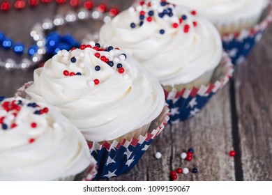 Patriotic 4th Of July Or Memorial Day Celebration Cupcakes On Rustic Wooden Table With Festive Red, White, And Blue Decorations.  