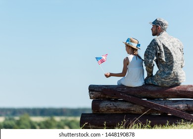 patriotic child holding american flag near veteran father while sitting in fence  - Powered by Shutterstock