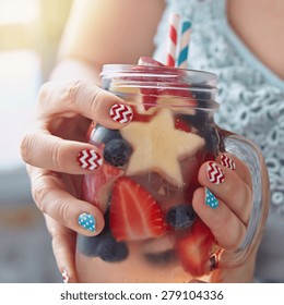 Patriotic Drink Cocktail With Strawberry, Blueberry And Apple In Woman's Hands