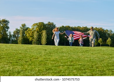 Patriotic family with huge usa flags outdoors. US soldier with his family in the park. - Powered by Shutterstock